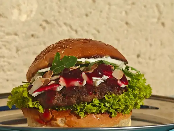 Burger Francja elegancja z camembertem i rukolą na turkusowym stole