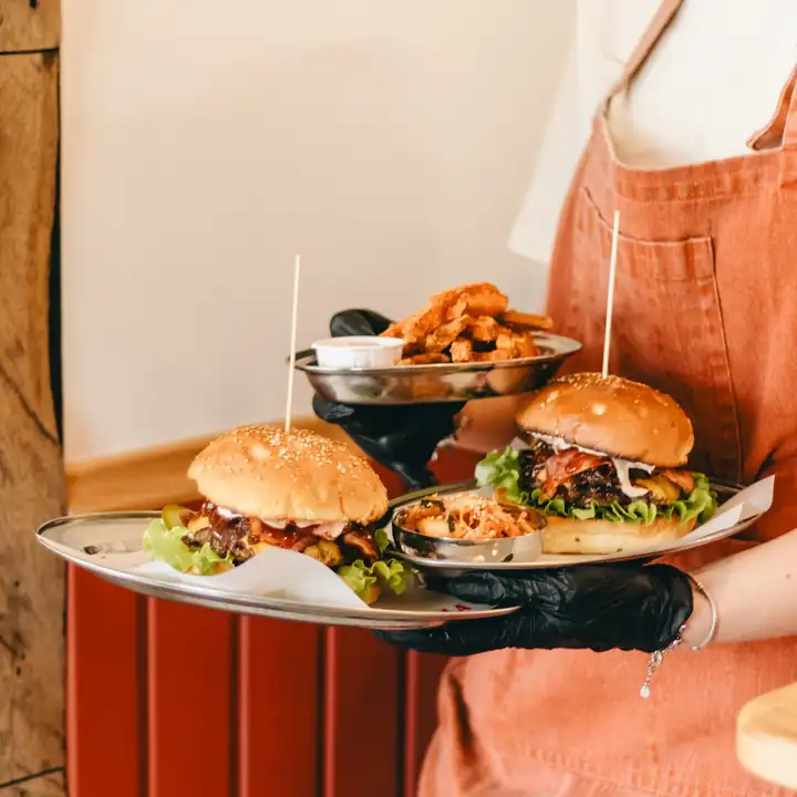 Obsługa niesie dwa burgery i frytki